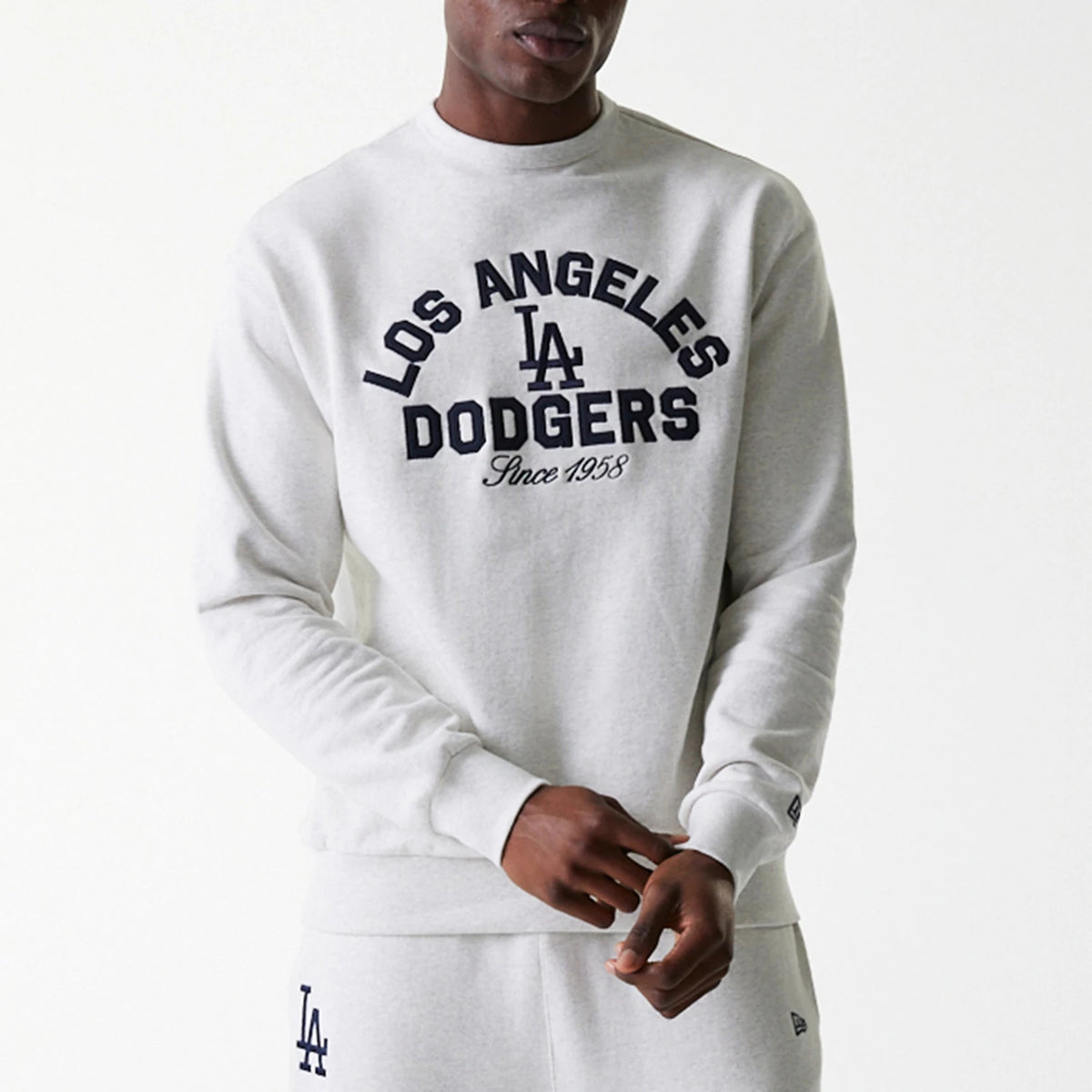 New Era LA Dodgers MLB Heritage Pastel Grey Oversized Crew Neck Sweater, front view on a model showing navy blue embroidered Los Angeles Dodgers lettering and logo across the chest, paired with matching sweatpants.