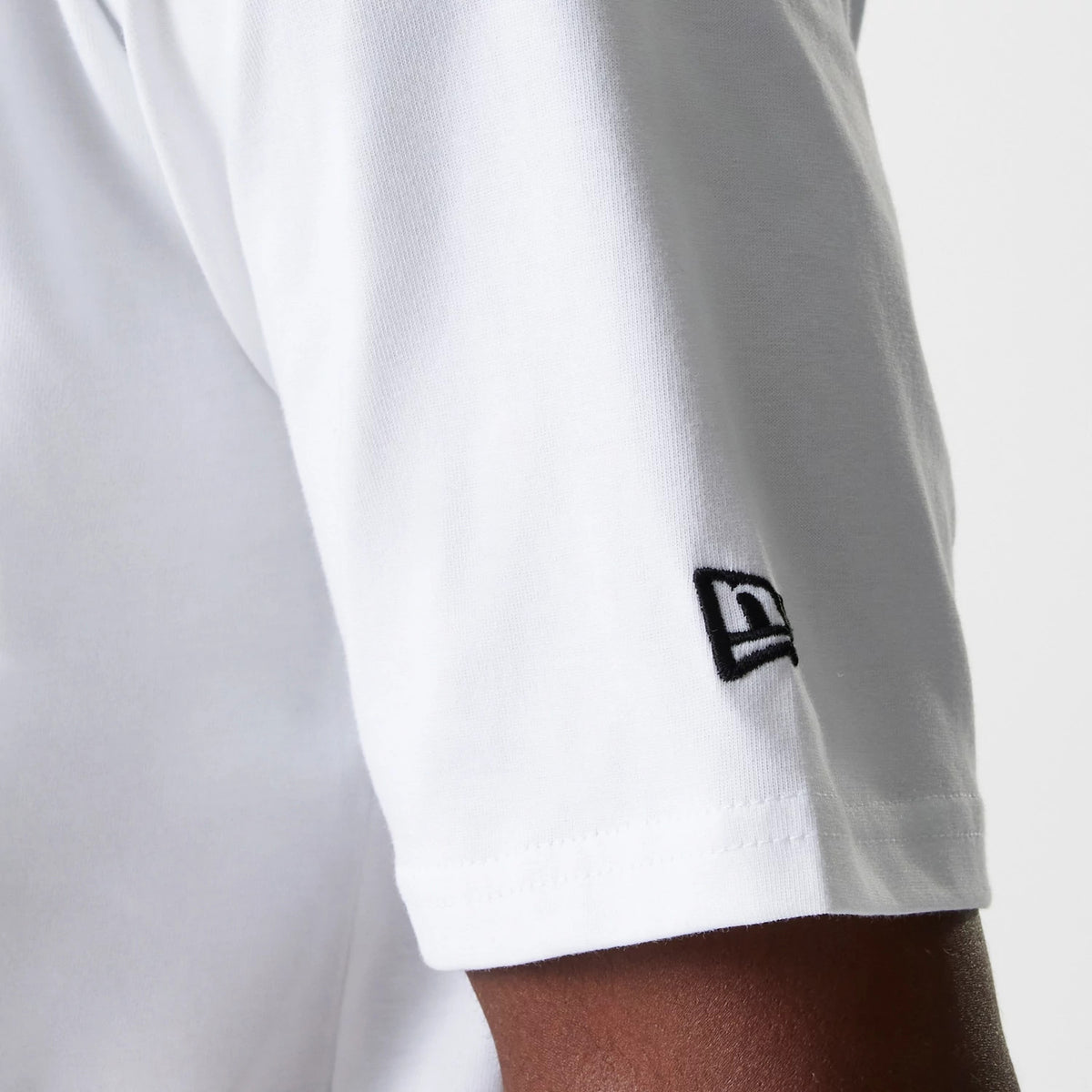 New Era New York Yankees MLB Baseball Graphic White Oversized T-Shirt, side view showing the short sleeve with a raised black New Era logo near the hem, set against the plain white fabric of the shirt.