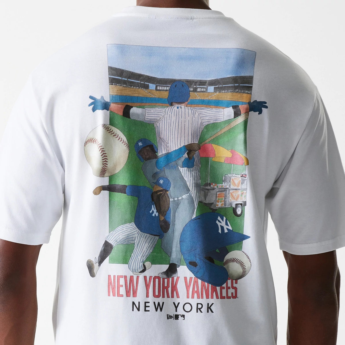 New Era New York Yankees MLB Baseball Graphic White Oversized T-Shirt, rear view showing a colourful graphic of three baseball players in action, a large baseball, a blue helmet, and stadium stands above the red New York Yankees New York text.