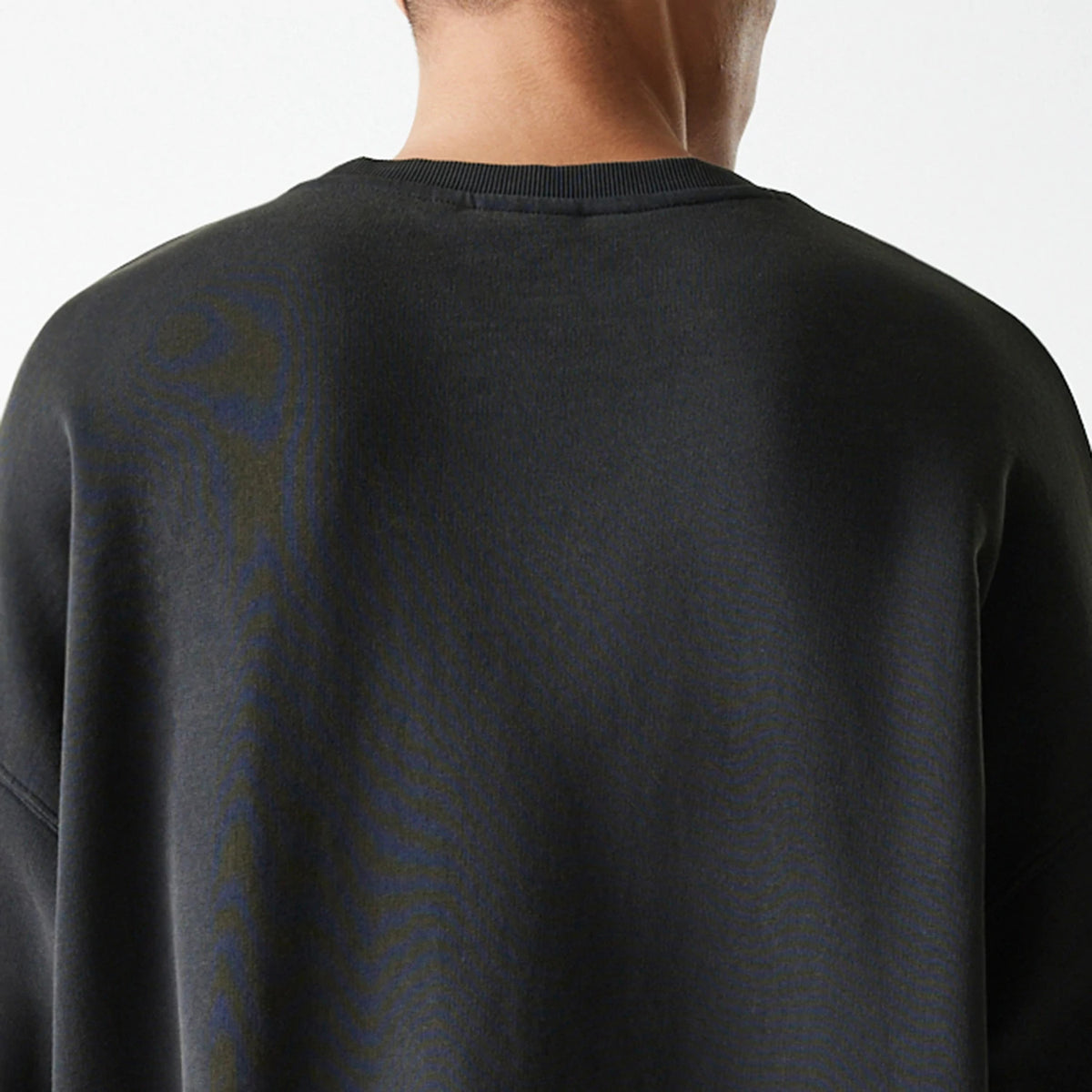 New Era Milwaukee Bucks NBA Washed Graphic Grey Oversized Crew Neck Sweater, back view on a model highlighting the relaxed drop shoulder design with ribbed collar detail against a plain grey fabric.