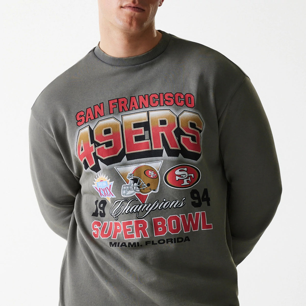 New Era San Francisco 49ers NFL Washed Super Bowl Grey Oversized Crew Neck Sweater, front view on a model showing the bold red and gold 49ERS lettering with football helmet and Super Bowl Champions graphics on the chest.