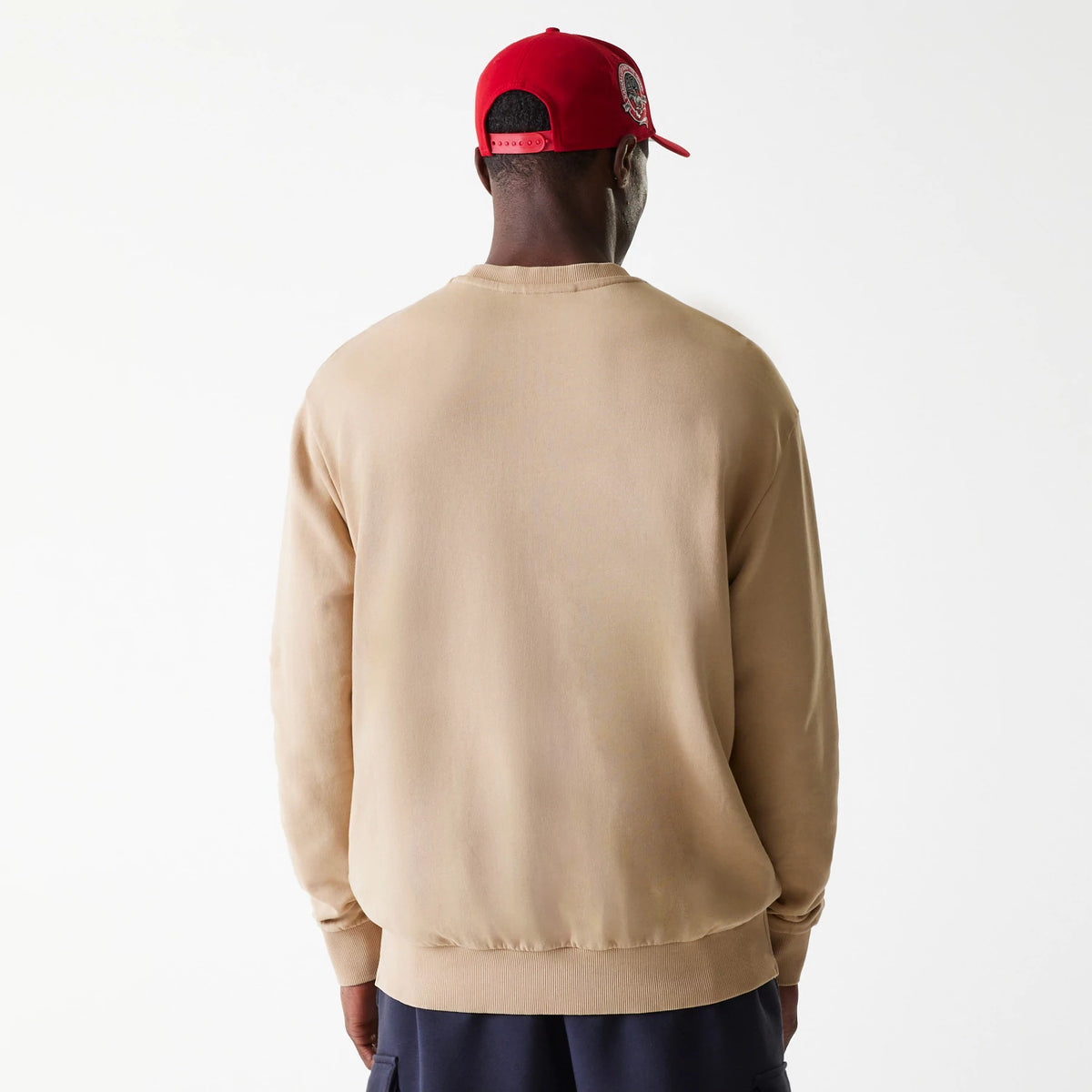 New Era Kansas City Chiefs NFL Washed Super Bowl Beige Oversized Crew Neck Sweater, back view on a model wearing a red cap, showcasing the dropped shoulder design and relaxed fit of the beige fabric.