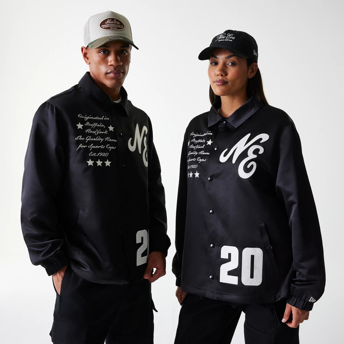 New Era Black Coaches Jacket, on-model view showing two models wearing black jackets with white NE logos on the chest, button-up fronts, script text alongside three stars, and the number 20 in large print near the hem.