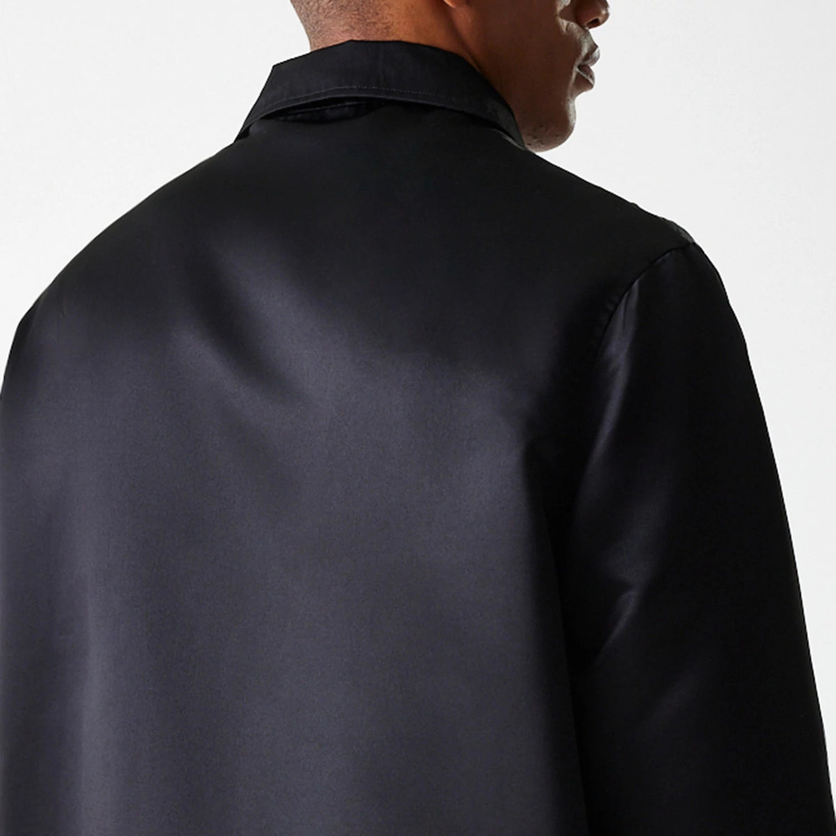 New Era Black Coaches Jacket, rear view showing the smooth black fabric and classic collar, with a visible seam running along the shoulder.