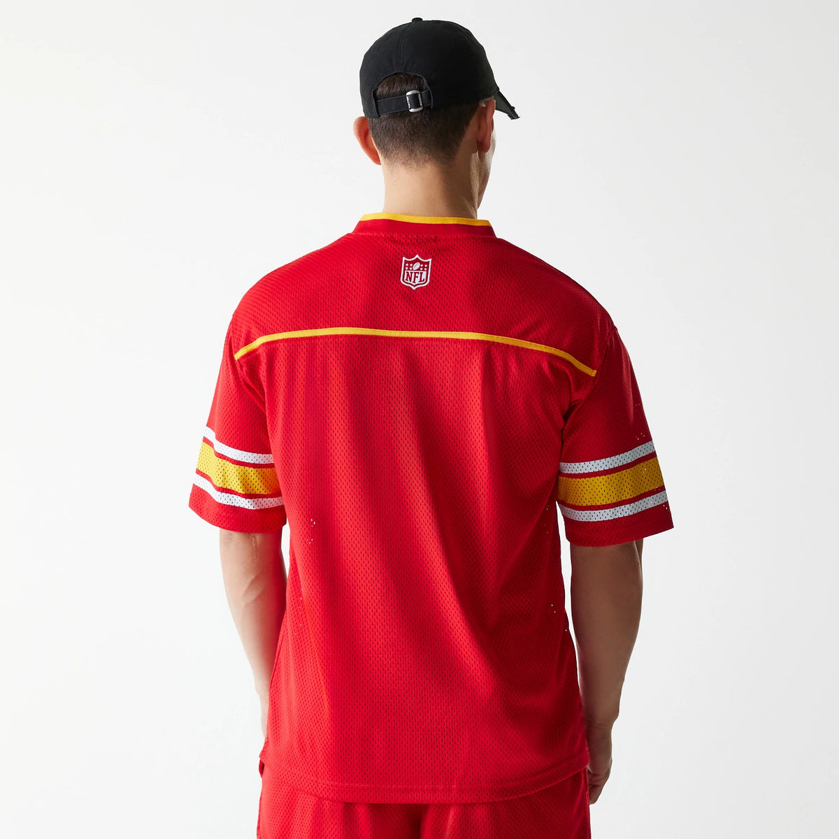 New Era Kansas City Chiefs NFL Mesh Red Jersey, back view on a model with a black cap, showing the white embroidered NFL logo below the neckline and yellow piping detail across the shoulders and sleeves.