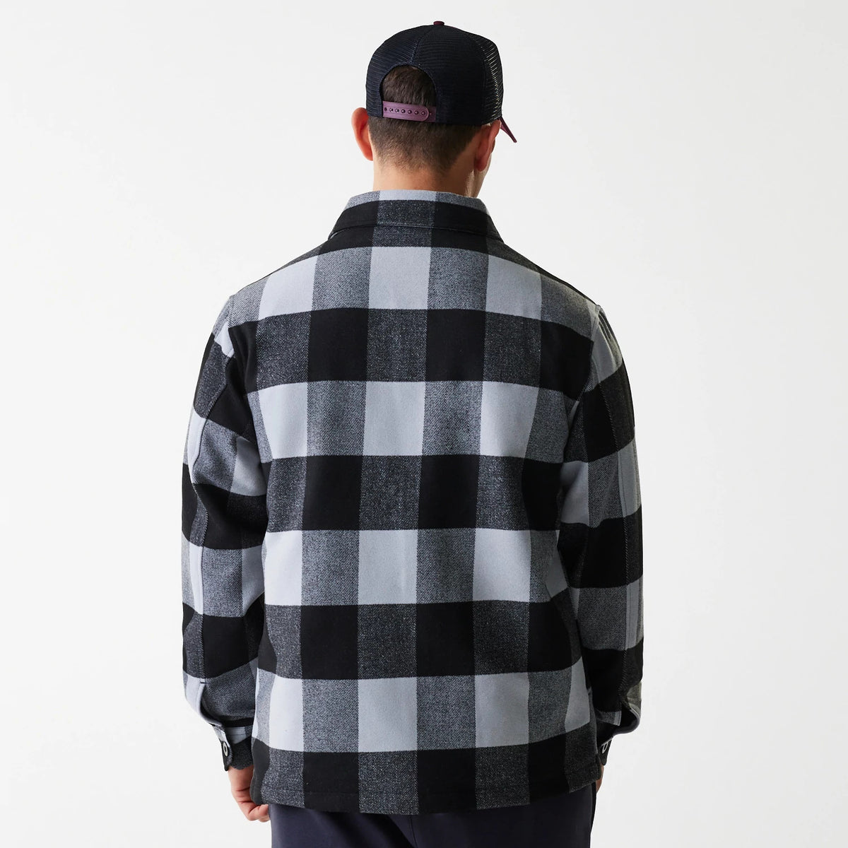 New Era Black Shacket, back view on a model wearing a black and purple snapback cap, showcasing the large black and grey check pattern across the back with buttoned cuffs on the sleeves.