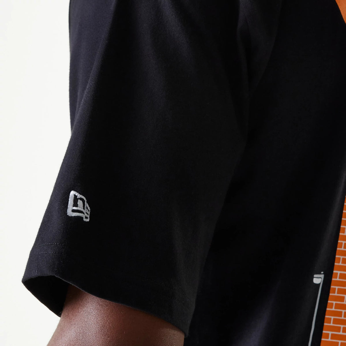 New Era Graffiti Graphic Black Oversized T-Shirt, side view showing a white debossed New Era logo near the hem of the short sleeve, with the plain black fabric extending across the shoulder towards the back.