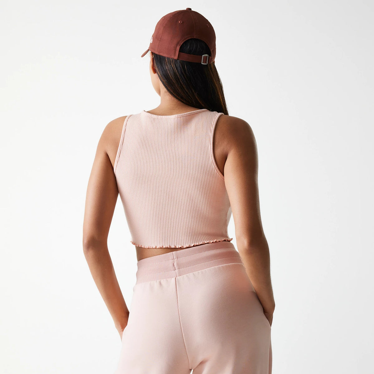 New Era New York Yankees Womens MLB Rib Pastel Pink Rib Tank Top, back view on a model with long hair, styled with pink ribbed fabric and cropped hem, paired with matching light pink trousers and a brown cap.