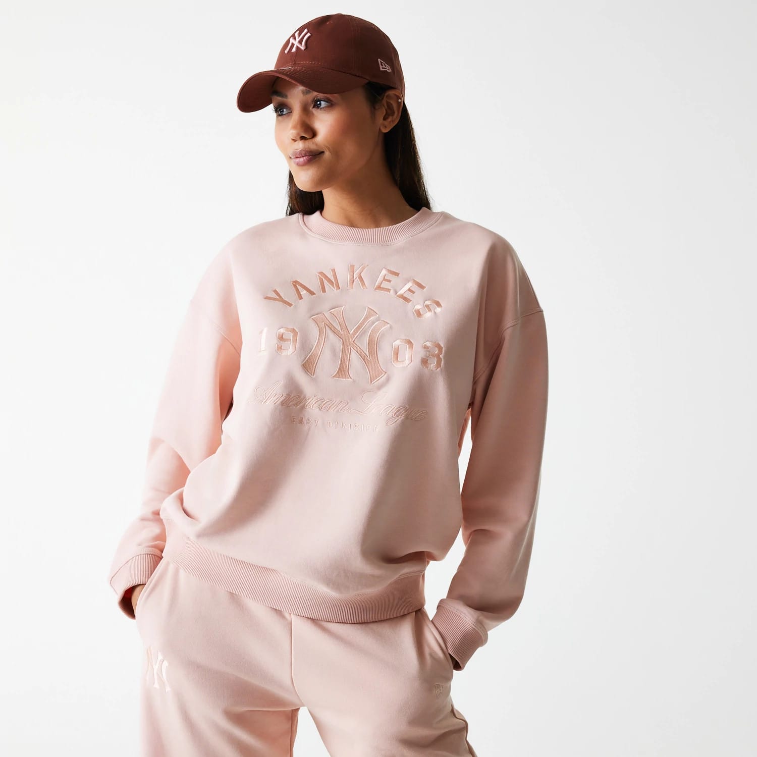 The Female model is wearing New York Yankees Womens MLB Tonal Graphic Pastel Pink Oversized Crew Neck Sweater 1