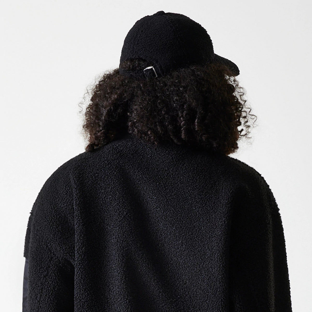 New Era LA Dodgers Womens MLB Black Oversized Sherpa Bomber Jacket, rear view showing the oversized black textured back, the high collar, and a black cap worn with a buckle strap closure at the back.