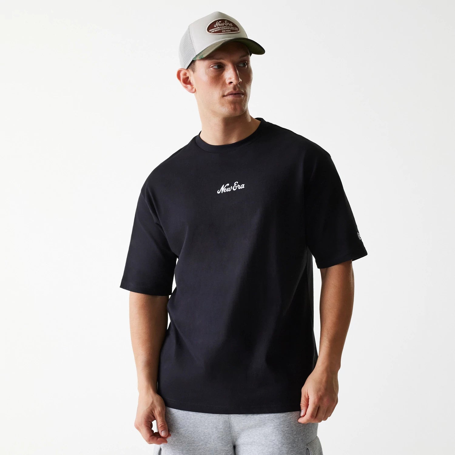The Male model is wearing New Era Trucker Patch Black Oversized T-Shirt 1