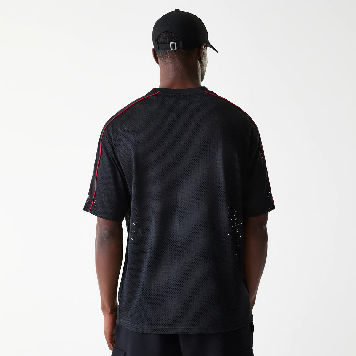 New Era Chicago Bulls NBA Piping Black Oversized Mesh T-Shirt, rear view showing the black mesh fabric with red piping along the shoulders, short sleeves, and a debossed New Era logo on the left sleeve near the hem.