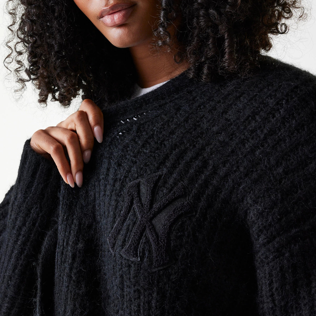 New Era New York Yankees Womens MLB Knit Black Cardigan, close-up on a model showing the textured black knit fabric with embroidered NY logo on the left chest, styled over a white top.