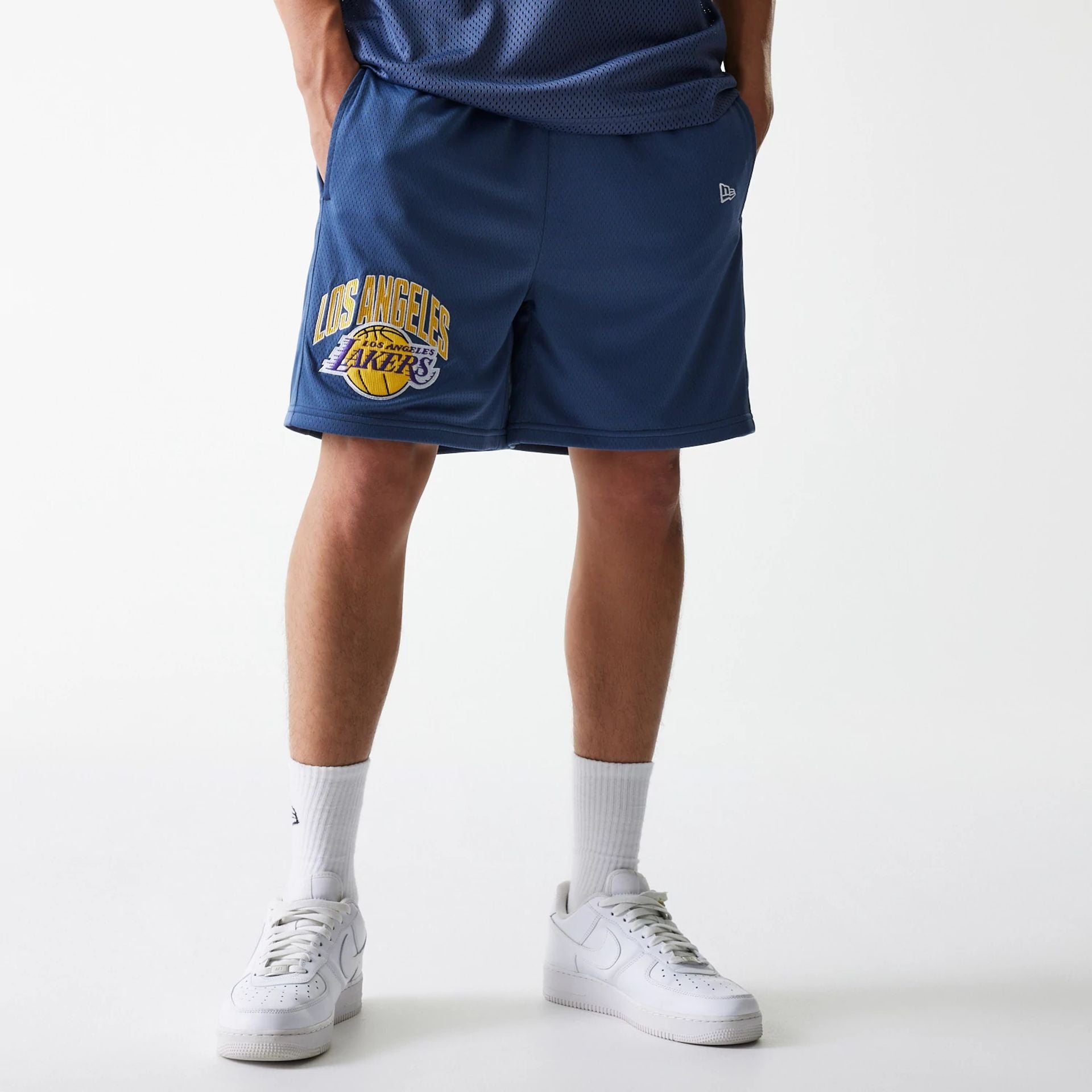 The Male model is wearing LA Lakers NBA Arch Graphic Dark Blue Mesh Shorts 1