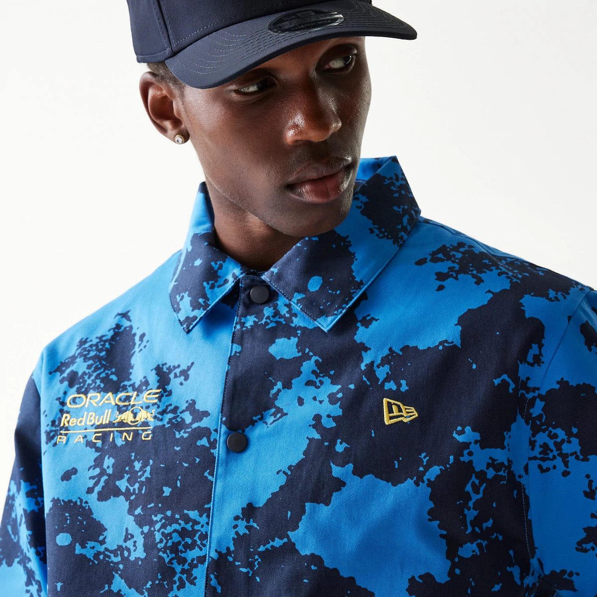 New Era Red Bull Racing Blue Oversized Coach Jacket, front view showing a blue abstract pattern with a raised New Era logo on the left chest and embroidered Oracle Red Bull Racing logos on the right chest.