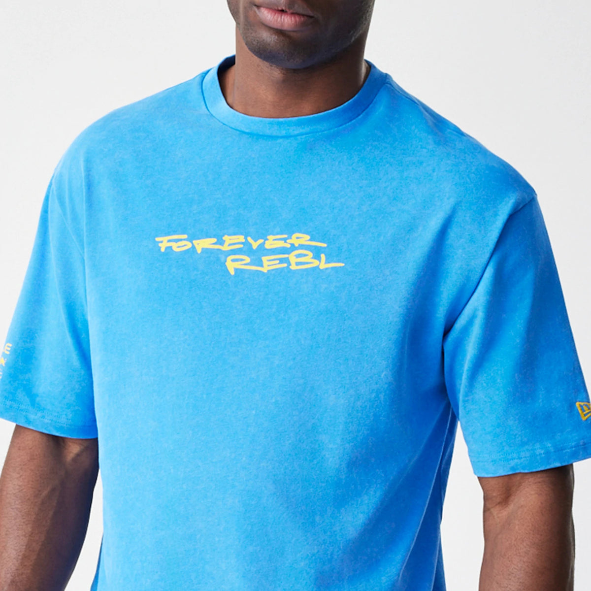 New Era Red Bull Racing Back Graphic Blue Oversized T-Shirt, front view on-model showing the blue colour with Forever Rebl printed in yellow on the chest, and a small New Era embroidered logo on the left sleeve.
