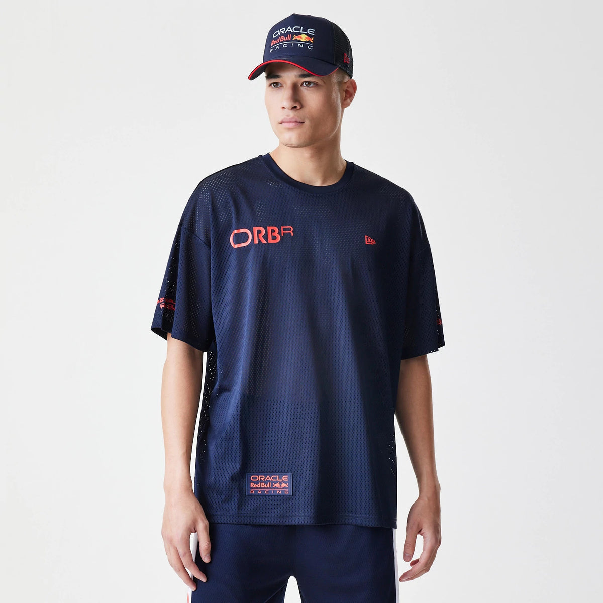 New Era Red Bull Racing Graphic Mesh Dark Blue Oversized T-Shirt, front view on-model showcasing the red ORBR graphic on the chest, an embroidered New Era logo on the left chest, and an Oracle Red Bull Racing patch near the hem.