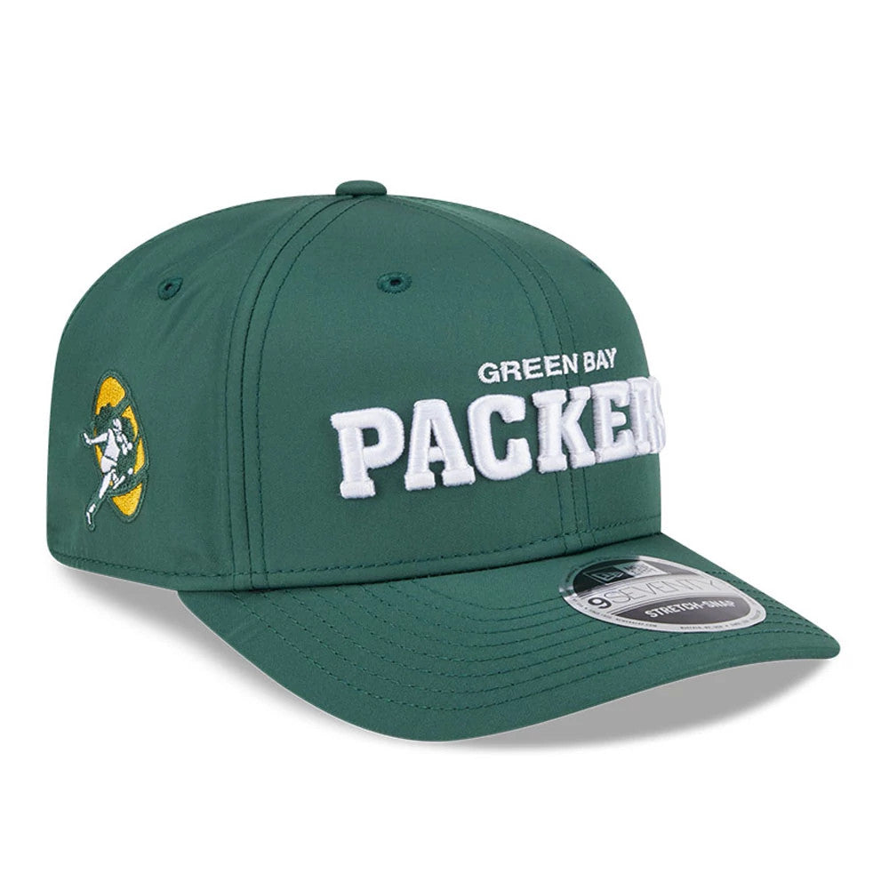 Green Bay Packers NFL Coach Dark Green New Era 9SEVENTY Stretch Snap Adjustable Cap, three-quarter view showing white raised embroidery logo on front panel, with a side patch logo and a grey 9SEVENTY size sticker on the dark green curved visor.