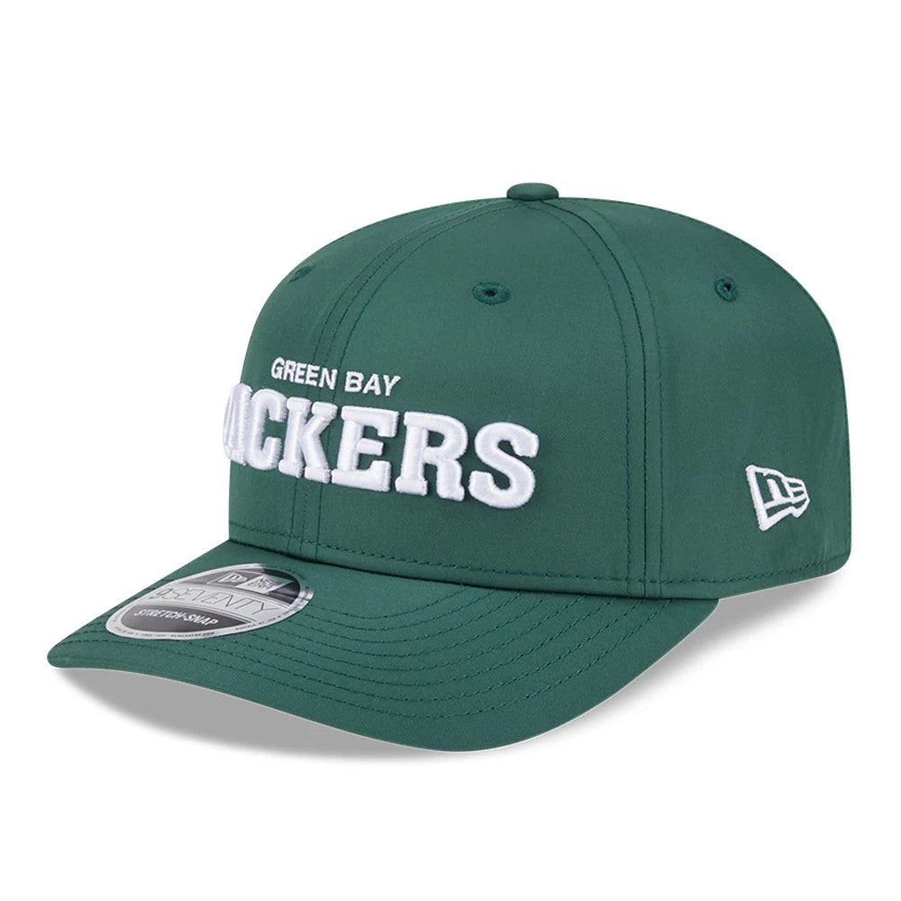 Green Bay Packers NFL Coach Dark Green New Era 9SEVENTY Stretch Snap Adjustable Cap, three-quarter view showing raised white Packers lettering on the front panel, dark green curved visor with a 9SEVENTY size sticker.