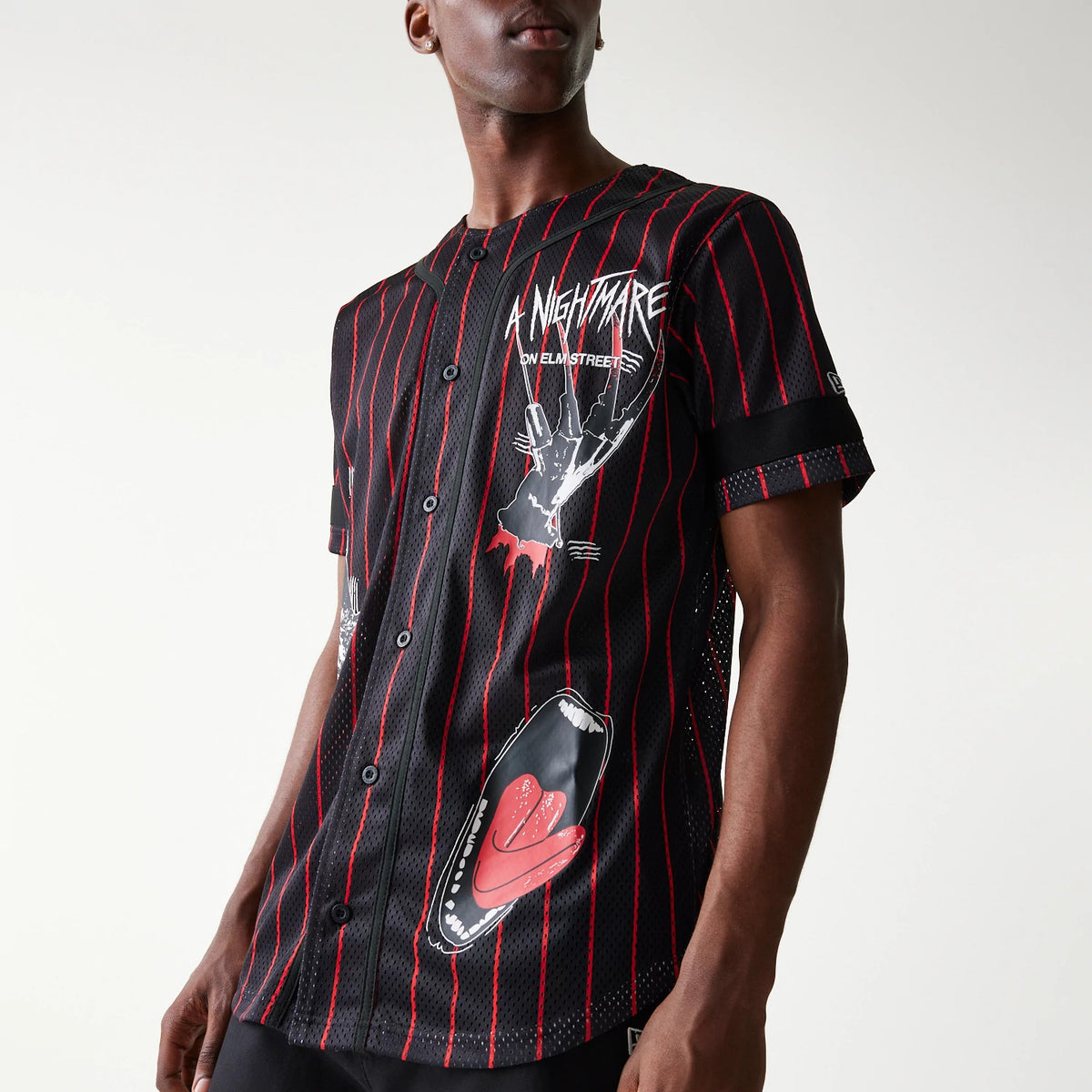 New Era A Nightmare On Elm Street Black Jersey, three-quarter view on a model featuring red pinstripes, Freddy Krueger claw graphic on the chest, and a printed open mouth with pink tongue on the lower front.