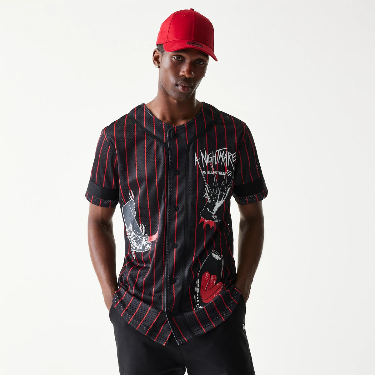 New Era A Nightmare On Elm Street Black Jersey, front view on a model with a red cap, featuring red stripes, Freddy Krueger glove graphic on the right side, and dripping text logo on the left chest.
