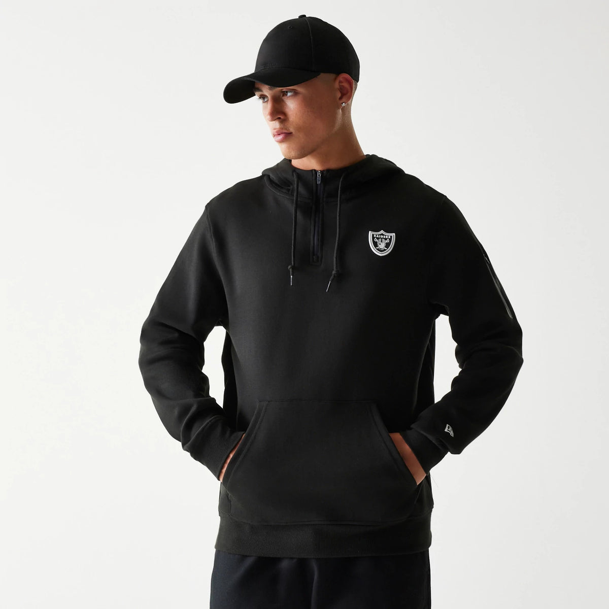New Era Las Vegas Raiders NFL 3RD Down Black Pullover Hoodie, front view on-model showing the Raiders shield embroidered on the chest, a half-zip design with drawstrings, a front pouch pocket and the New Era logo embroidered on the left cuff.