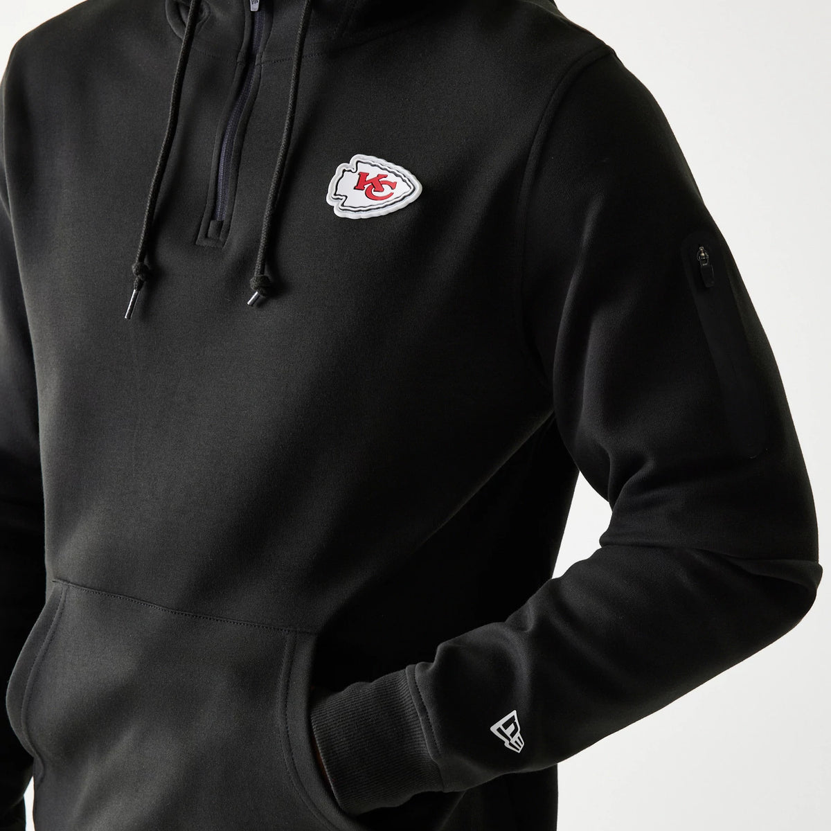 New Era Kansas City Chiefs NFL 3RD Down Black Pullover Hoodie, front three-quarter view showing a white embroidered Chiefs logo on the chest, a zip pocket on the arm and the white embroidered New Era logo above the cuff.