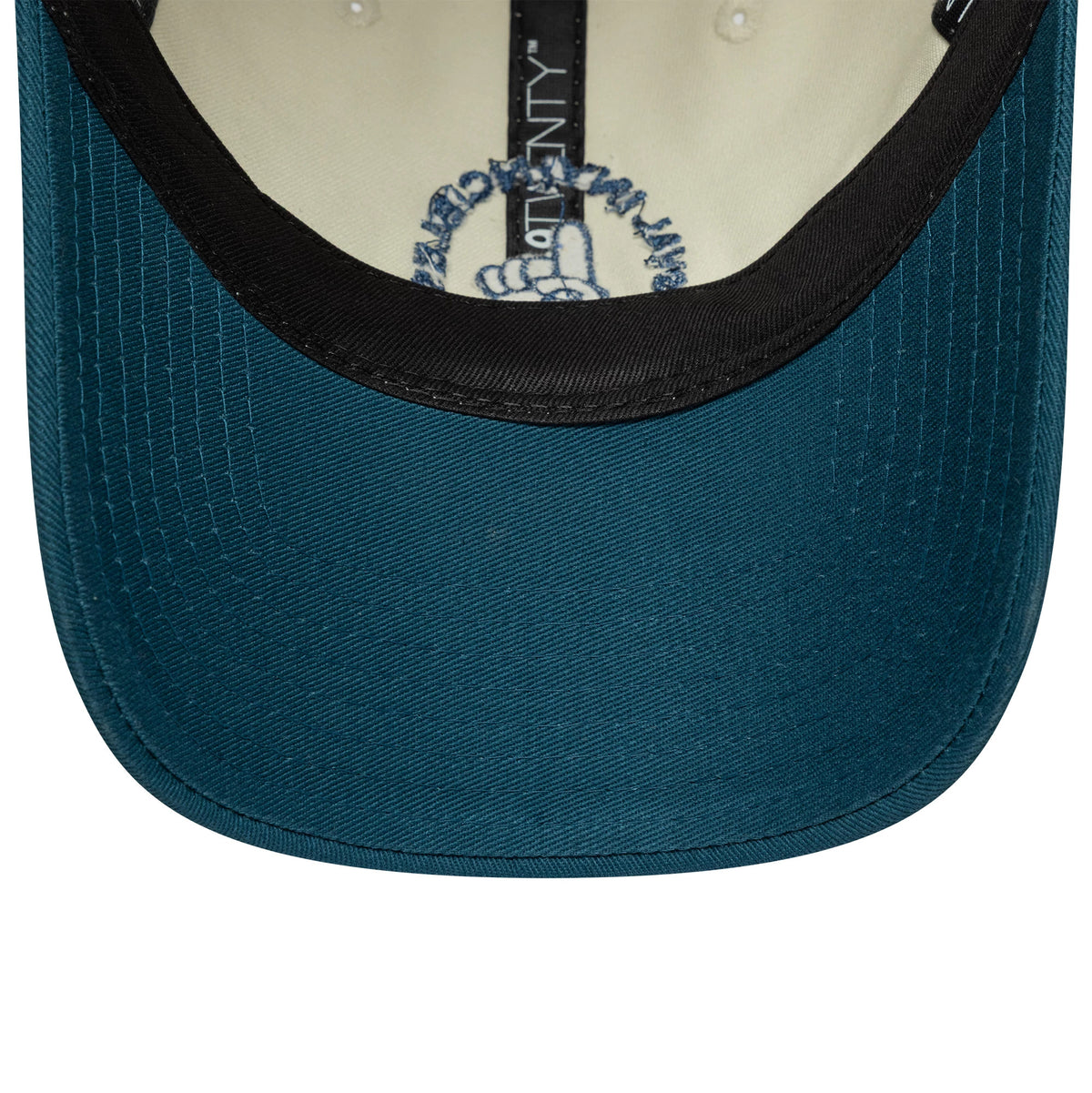 Oval Invincibles The Hundred 2025 Contrast Light Beige New Era 9TWENTY Adjustable Cap, inside view showing a black sweatband, light beige lining, and a teal undervisor with detailed black stitching and a logo print near the sweatband.
