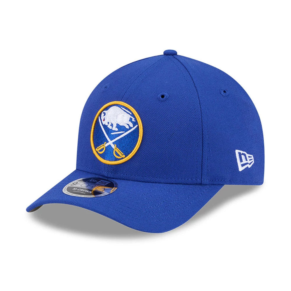 Buffalo Sabres NHL Team Blue New Era 9FORTY M-Crown Adjustable Cap, three-quarter view showing a raised embroidered white buffalo and crossed sabres logo on the front panel, curved blue visor with 9FORTY size sticker.