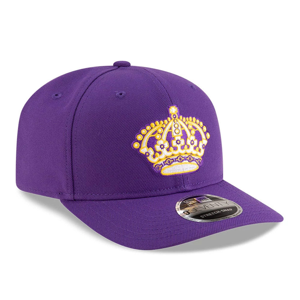 LA Kings NHL Team Purple New Era 9SEVENTY Stretch Snap Adjustable Cap, front view showing a raised gold and white embroidered crown logo on the structured purple crown with a 9SEVENTY size sticker on the curved visor.