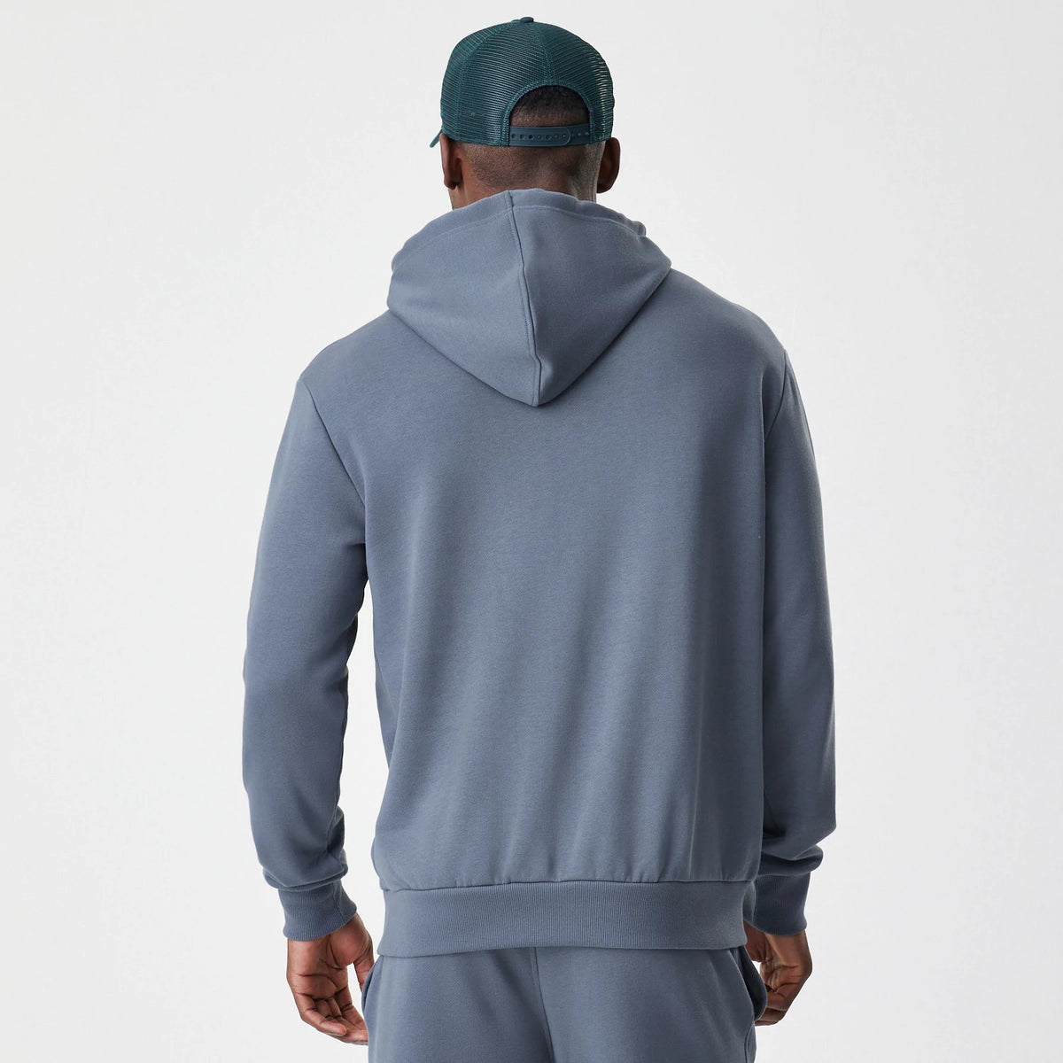 New Era LA Dodgers MLB Midi League Essential Dark Grey Oversized Pullover Hoodie, back view on a model showcasing the plain dark grey hood and ribbed hem and cuffs, styled with a matching dark grey track bottom.