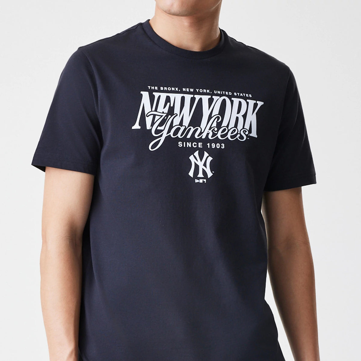 New Era New York Yankees MLB Script Graphic Navy T-Shirt, front view on-model highlighting the large white printed New York Yankees script across the chest with the NY logo underneath, complemented by short sleeves.