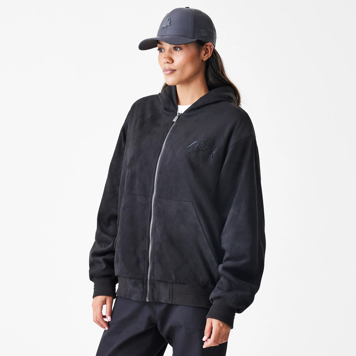 New Era LA Lakers NBA Suede Black Hooded Jacket, front view on-model showing the zip-up design with an embroidered LA Lakers logo on the left chest, ribbed cuffs and hem, and a roomy hood for casual wear.