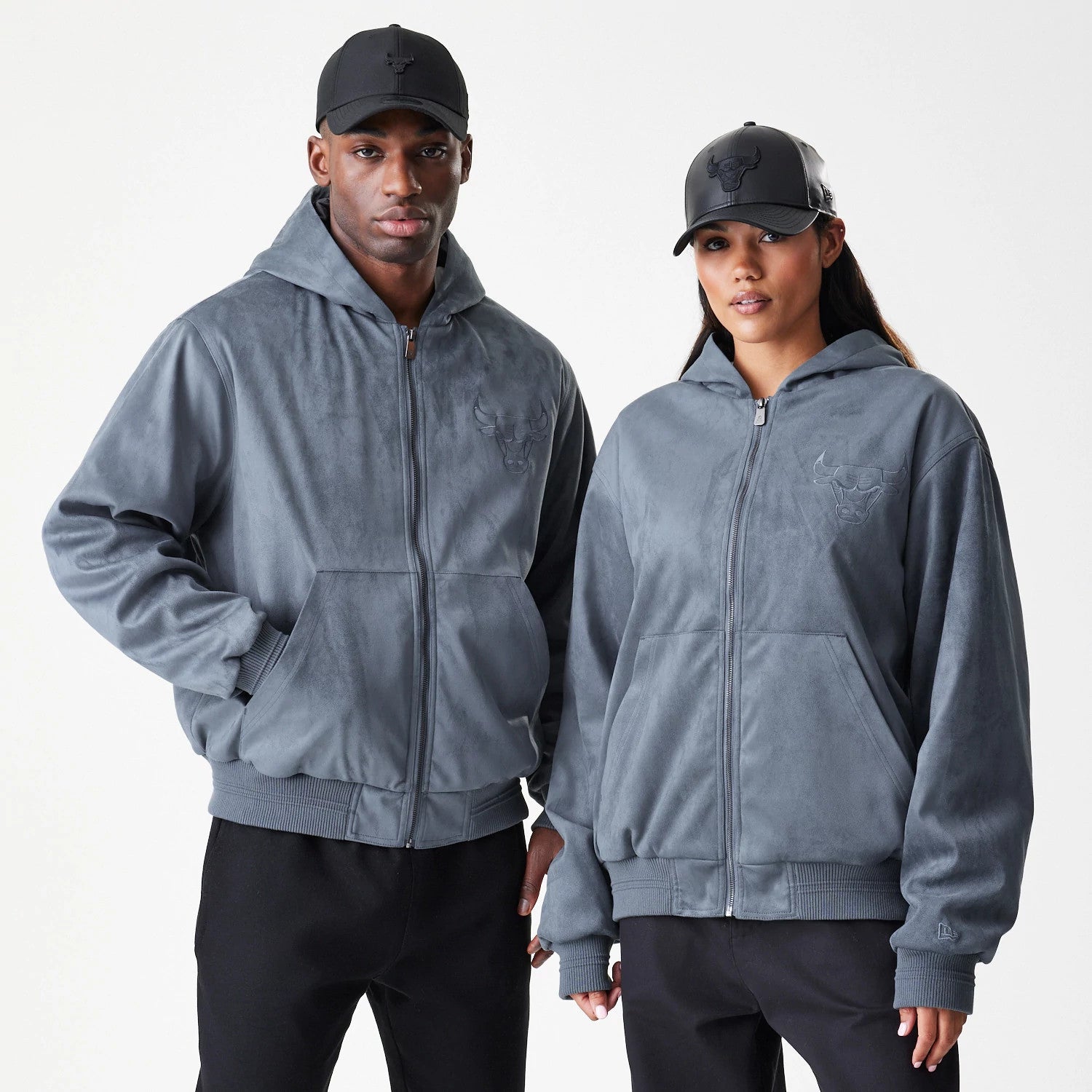 New Era Chicago Bulls NBA Suede Dark Grey Jacket, front view on models showcasing the soft grey jacket with a embroidered Bulls logo on the left chest, full zip closure in the centre and ribbed cuffs at the wrists and hem.