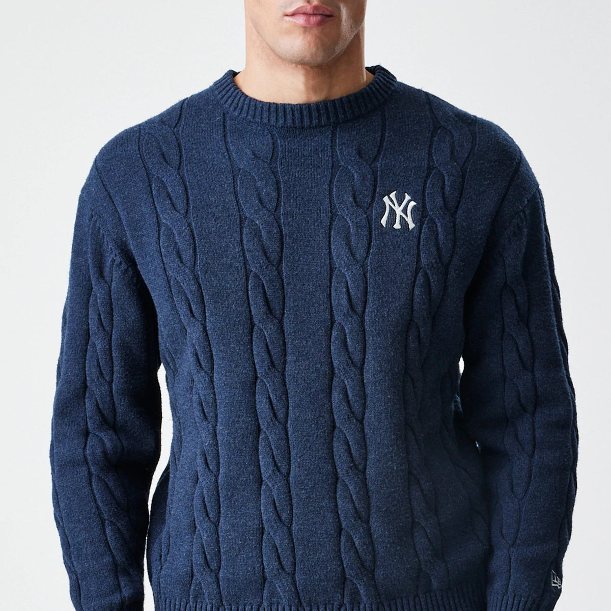New Era New York Yankees MLB Cable Knit Navy Knitted Sweater, front view on a model displaying the intricate cable knit design, white NY logo embroidered on the upper left chest, and ribbed neckline and cuffs.