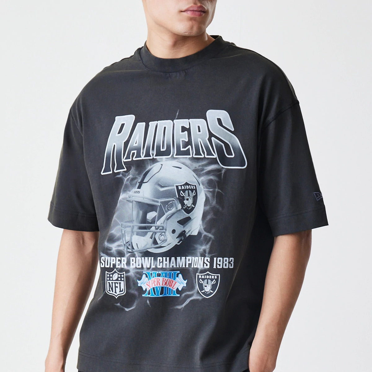New Era Las Vegas Raiders NFL Washed Boxy Dark Grey Oversized T-Shirt, front view on-model featuring a Raiders helmet graphic with Super Bowl Champions 1983 lettering and the embroidered New Era logo on the left sleeve.