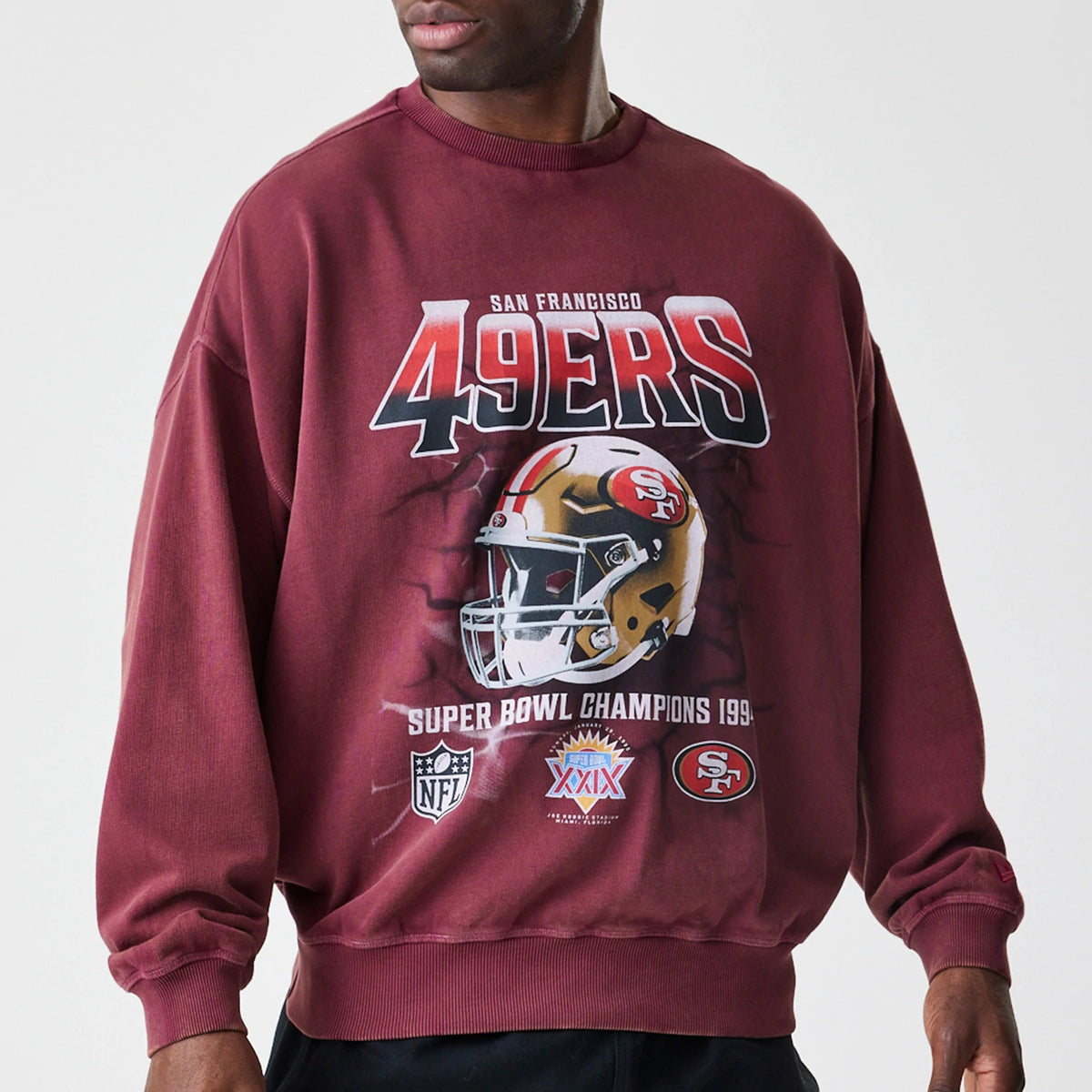New Era San Francisco 49ers NFL Washed Boxy Dark Red Oversized Crew Neck Sweater, front view on a model featuring large 49ERS lettering, a centred football helmet graphic, NFL and team logos with Super Bowl champions text on the lower front.