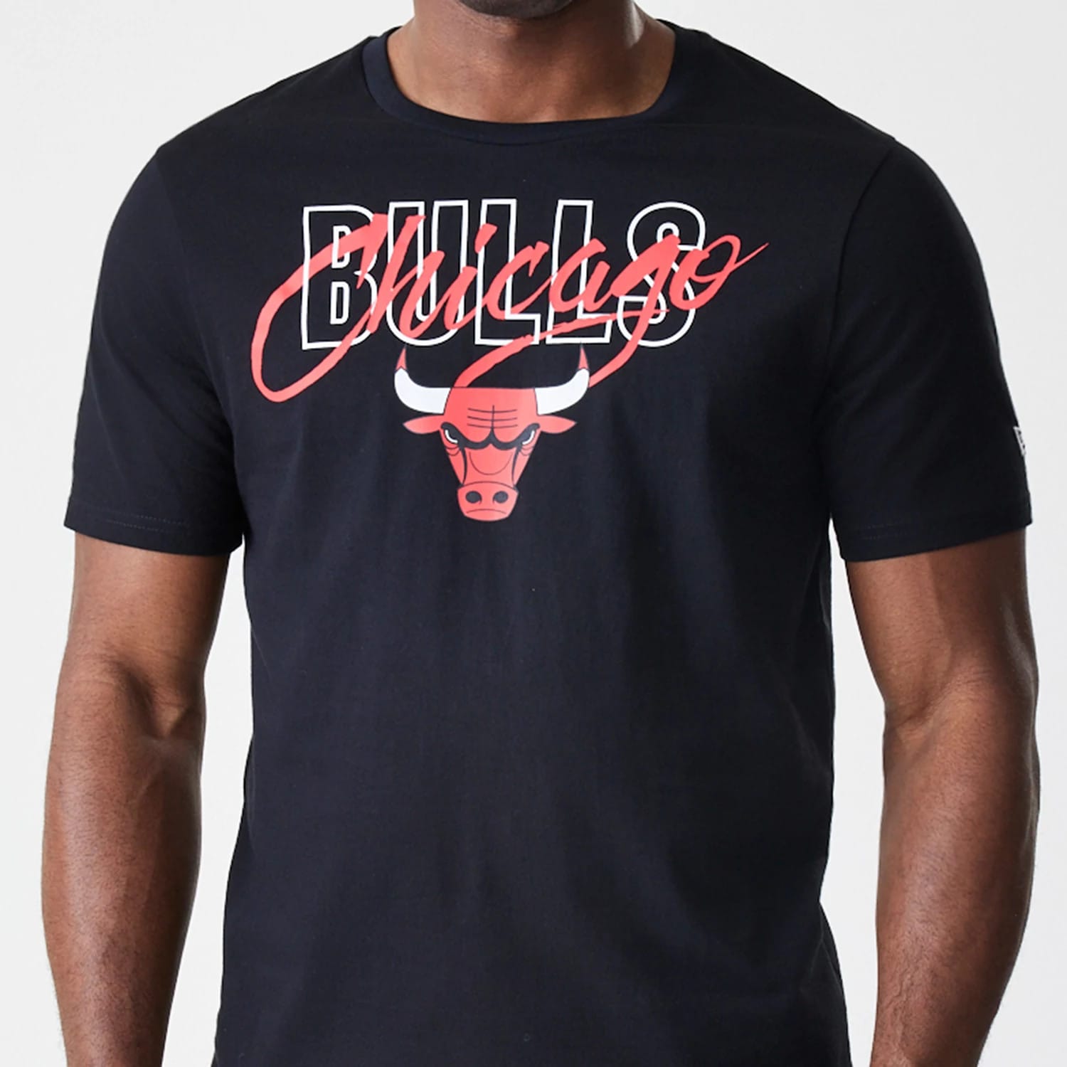 New Era Chicago Bulls NBA Script Black T-Shirt, front view showing a red Bulls logo and script overlaid on white block letters, worn by a model with a focus on the graphic detail across the chest.