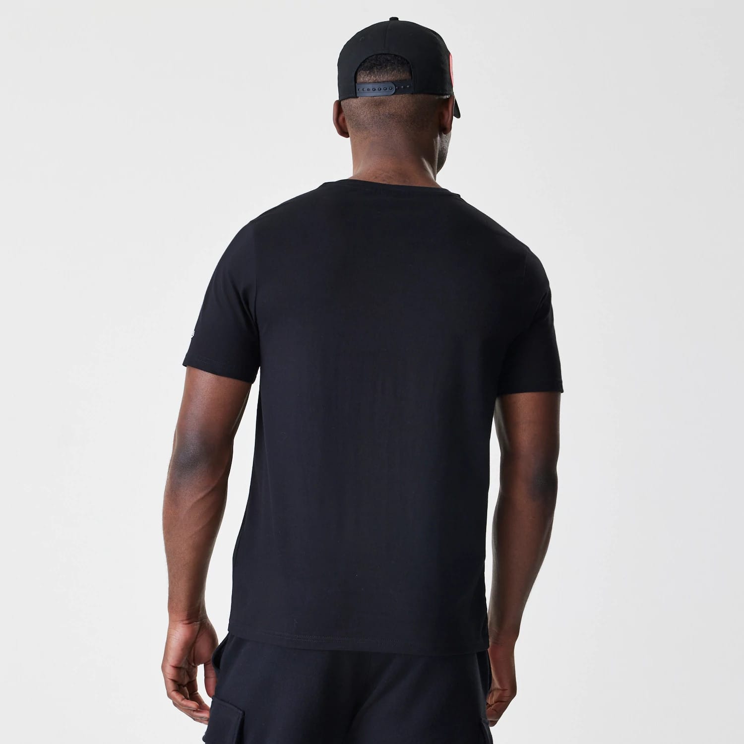 New Era Chicago Bulls NBA Script Black T-Shirt, back view on a model with a cap, showing a plain black back with short sleeves and a crew neckline, no graphics or logos.