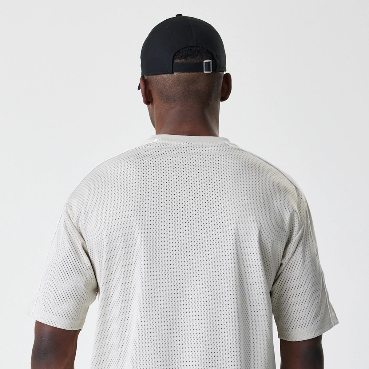 New Era LA Lakers NBA Piping Light Beige Oversized Mesh T-Shirt, back view on a model paired with a black cap, displaying a plain mesh design with piping detail along the shoulders and sleeves.
