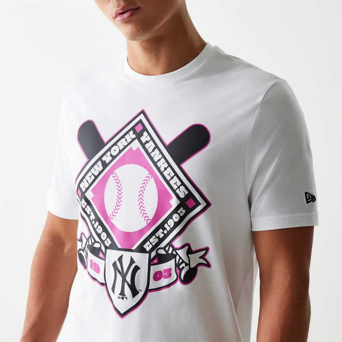 New Era New York Yankees MLB Baseball Graphic White T-Shirt, front view on a model highlighting the pink and black graphic with baseball bat motifs and printed New York Yankees text and logo, small embroidered New Era logo on the left sleeve.