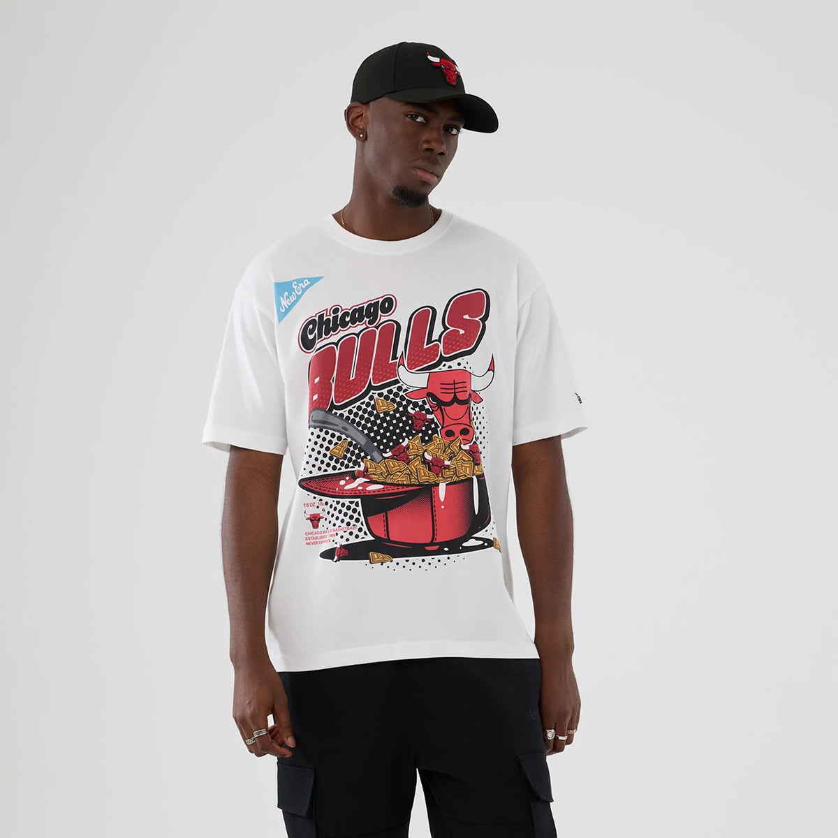 New Era Chicago Bulls NBA Lifestyle Graphic White T-Shirt, front view on-model showcasing a graphic of a bull with lettering and a New Era printed logo on the upper left, styled with black cargo shorts and a black cap featuring team branding.