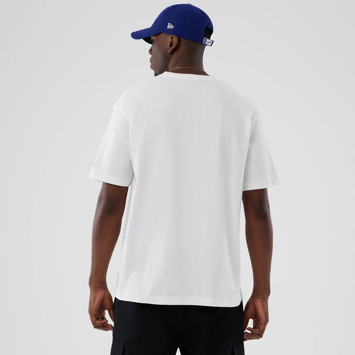 New Era LA Dodgers MLB Lifestyle Graphic White T-Shirt, back view on a model styled with a blue cap, displaying the plain white fabric across the back and sleeves of the T-shirt with no graphics or logos.