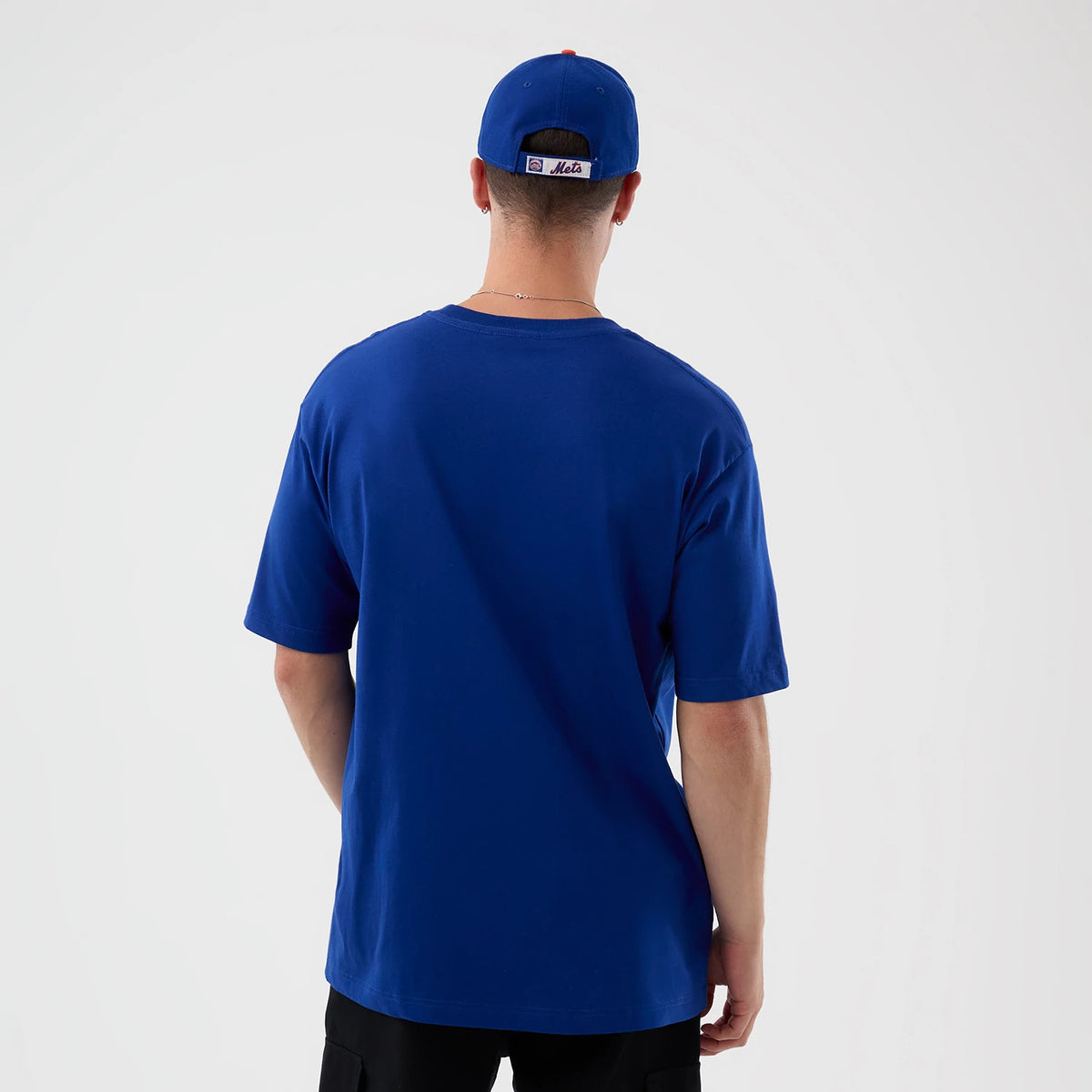 New Era New York Mets MLB Sport Classic Blue T-Shirt, back view on a model with a matching blue cap, featuring a plain blue back with short sleeves, and the cap displaying an embroidered Mets logo on the strap.