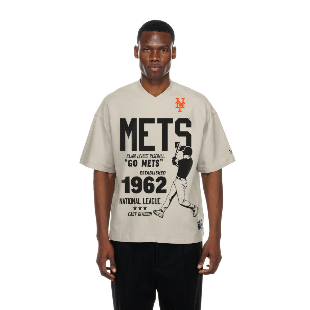 New Era New York Mets MLB Throwback Prep Light Beige T-Shirt, front view on-model featuring a large black METS text, a baseball player graphic, the number 1962, and an orange embroidered New Era logo on the chest.