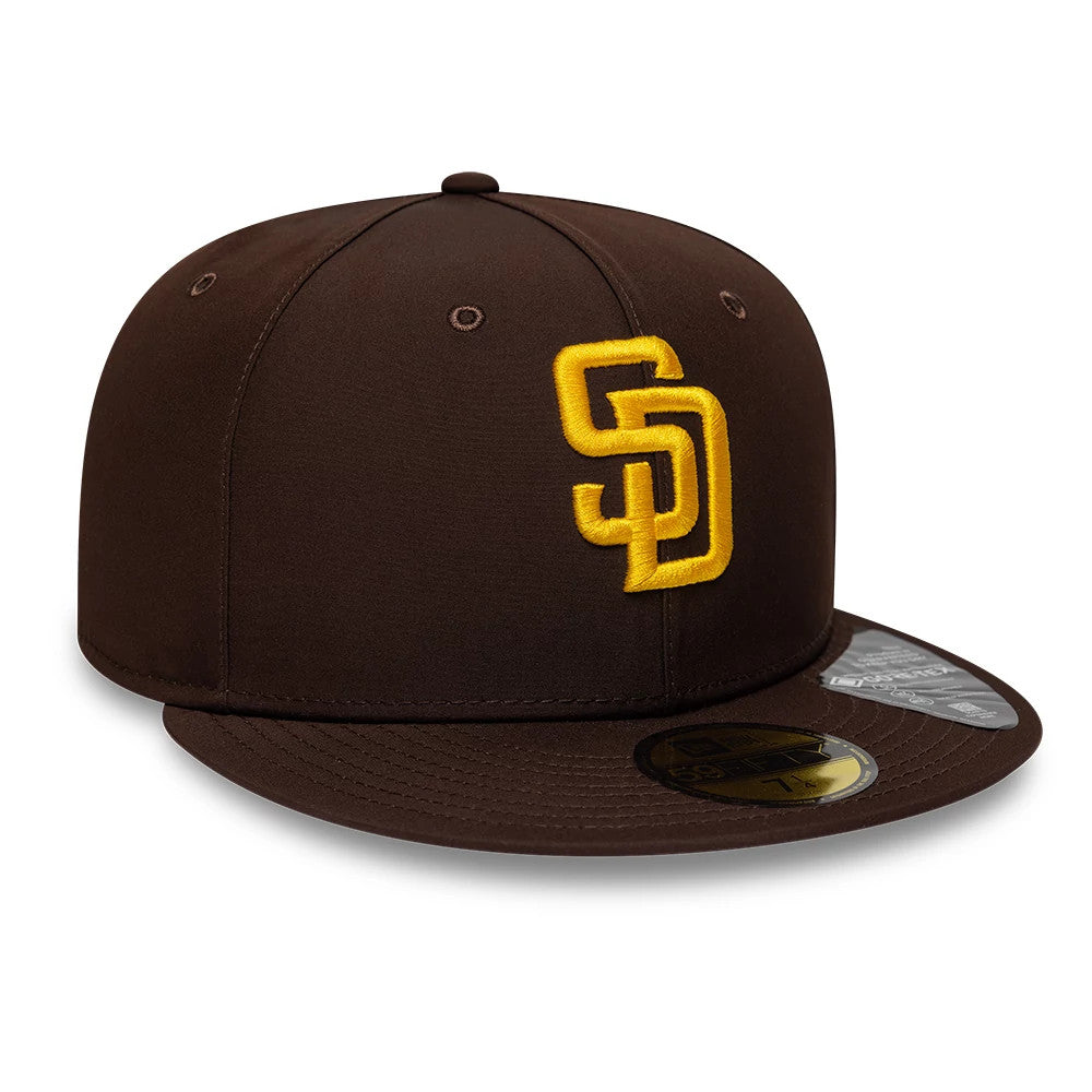 San Diego Padres MLB Gore-Tex Dark Brown New Era 59FIFTY Fitted Cap, three-quarter view showing a gold SD logo in raised embroidery on the front panel, a flat brown visor with a gold 59FIFTY size sticker, and eyelets on each panel.