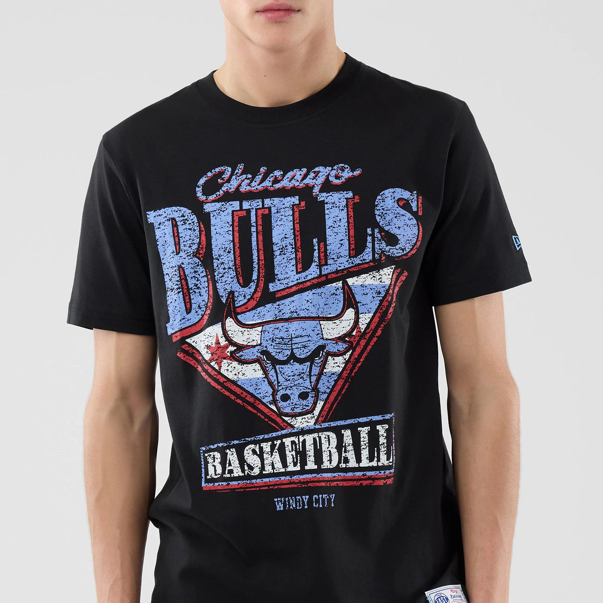 New Era Chicago Bulls NBA City Edition Black T-Shirt, front view showing a large graphic with distressed blue Chicago Bulls lettering above a stylised bull's head, basketball text below, and a small embroidered New Era logo on the sleeve.