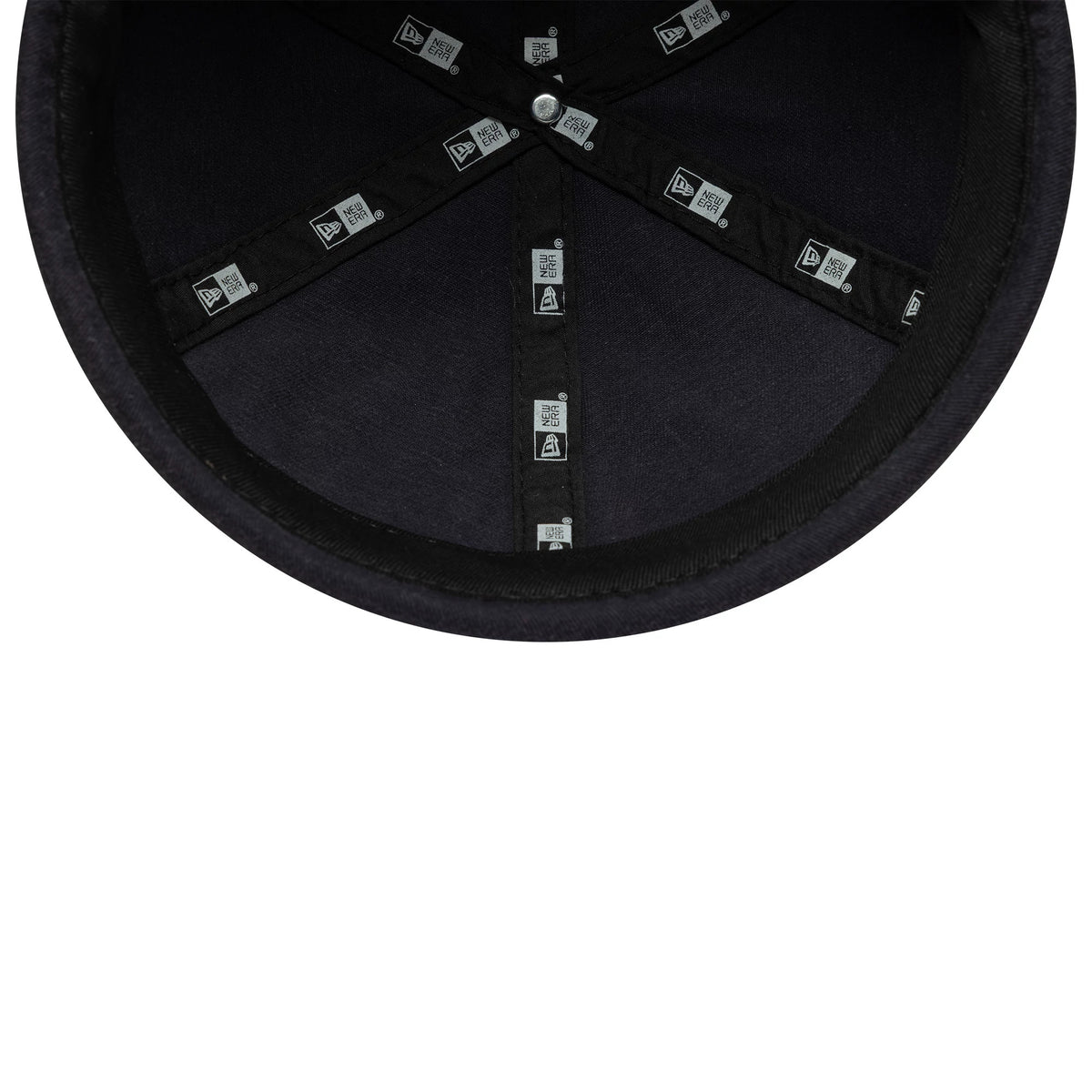 New Era Washed Cotton Navy Docker Adjustable Hat, inside view showing black taping with repeated New Era logos, a black sweatband around the edge, and a navy undervisor with a top button at the centre.