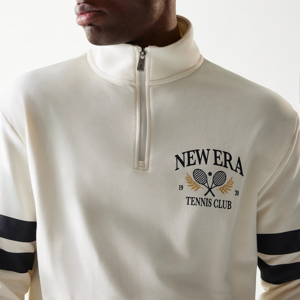 New Era Open White Oversized 1/4 Zip Sweater, front view on a model featuring a high collar and embroidered New Era Tennis Club logo with crossed rackets and laurel underneath the zippered neckline.
