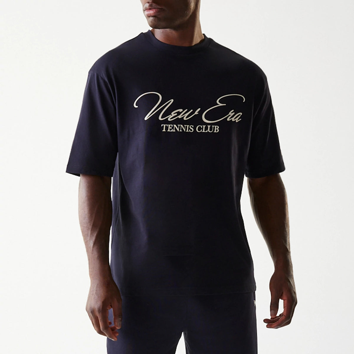 New Era Navy Oversized T-Shirt, front view showing a model wearing the navy T-shirt with New Era Tennis Club in large white script across the chest, short sleeves and a relaxed fit.